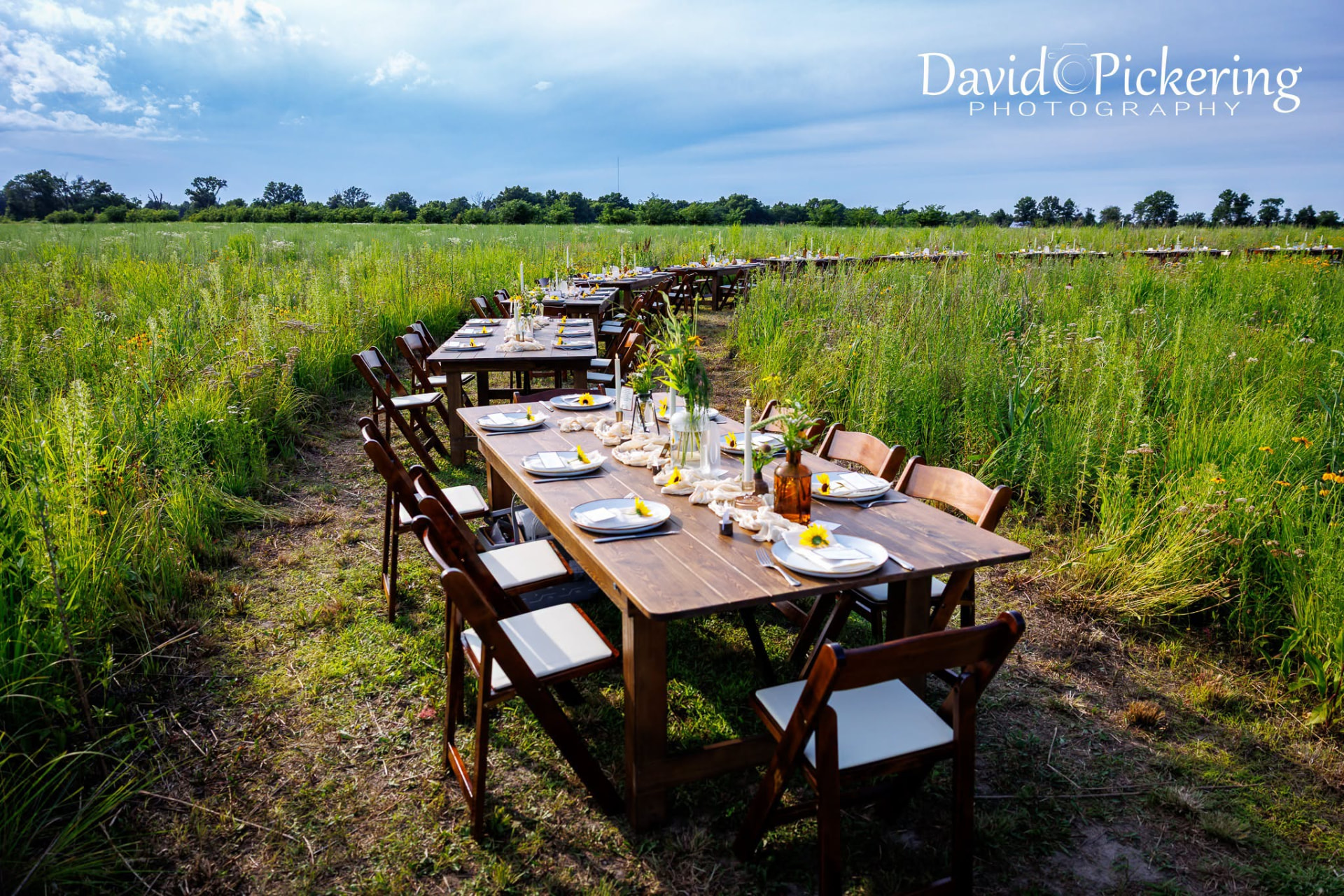 Long farm tables set for dinner in the wildflower prairie at Callaway Fields